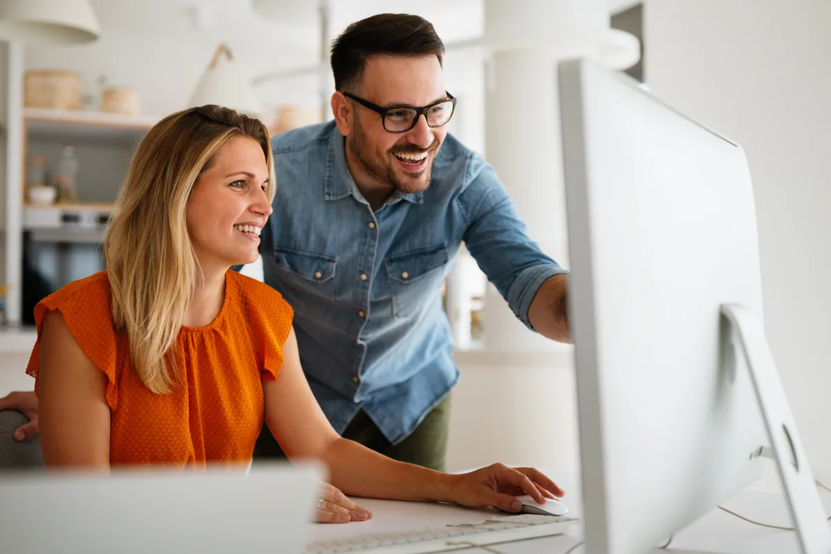 Two colleagues working together at a desktop computer
